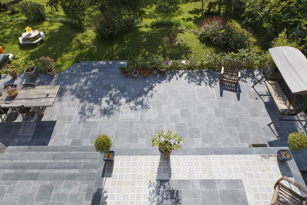 Een terras uit natuursteen in een grote tuin.