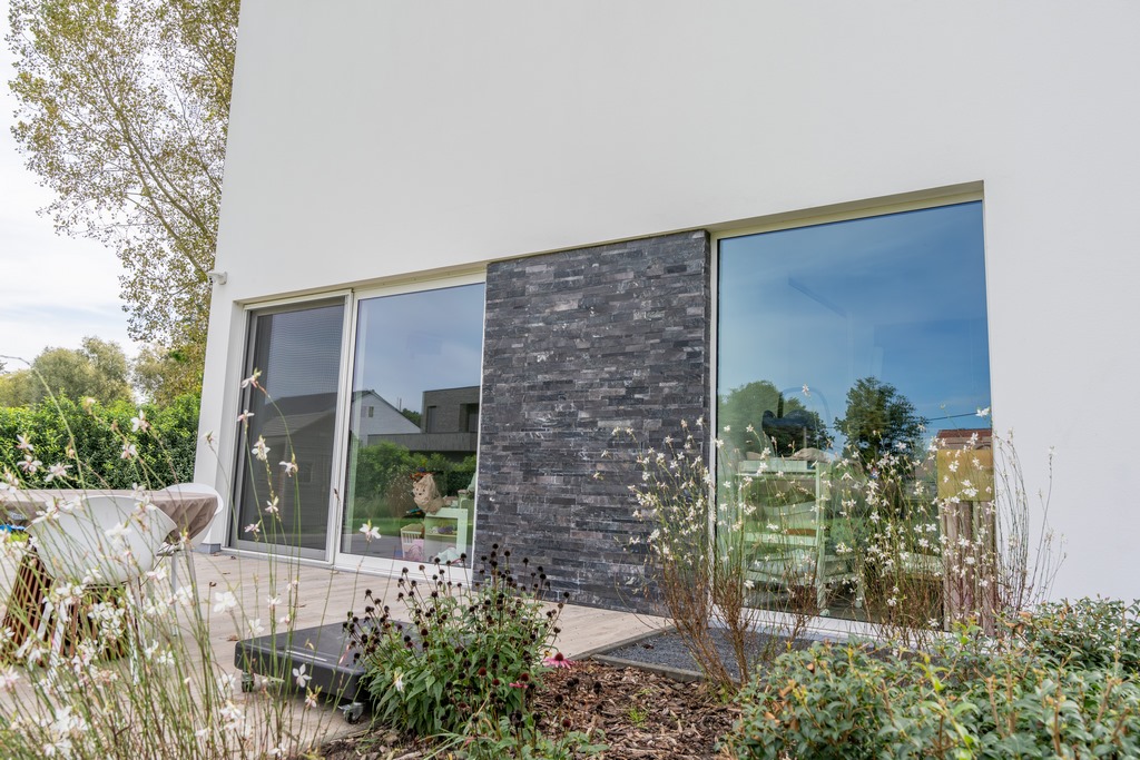 Buitenaanzicht van een moderne woning waarbij steenstrips zijn geplaatst tussen 2 ruiten.