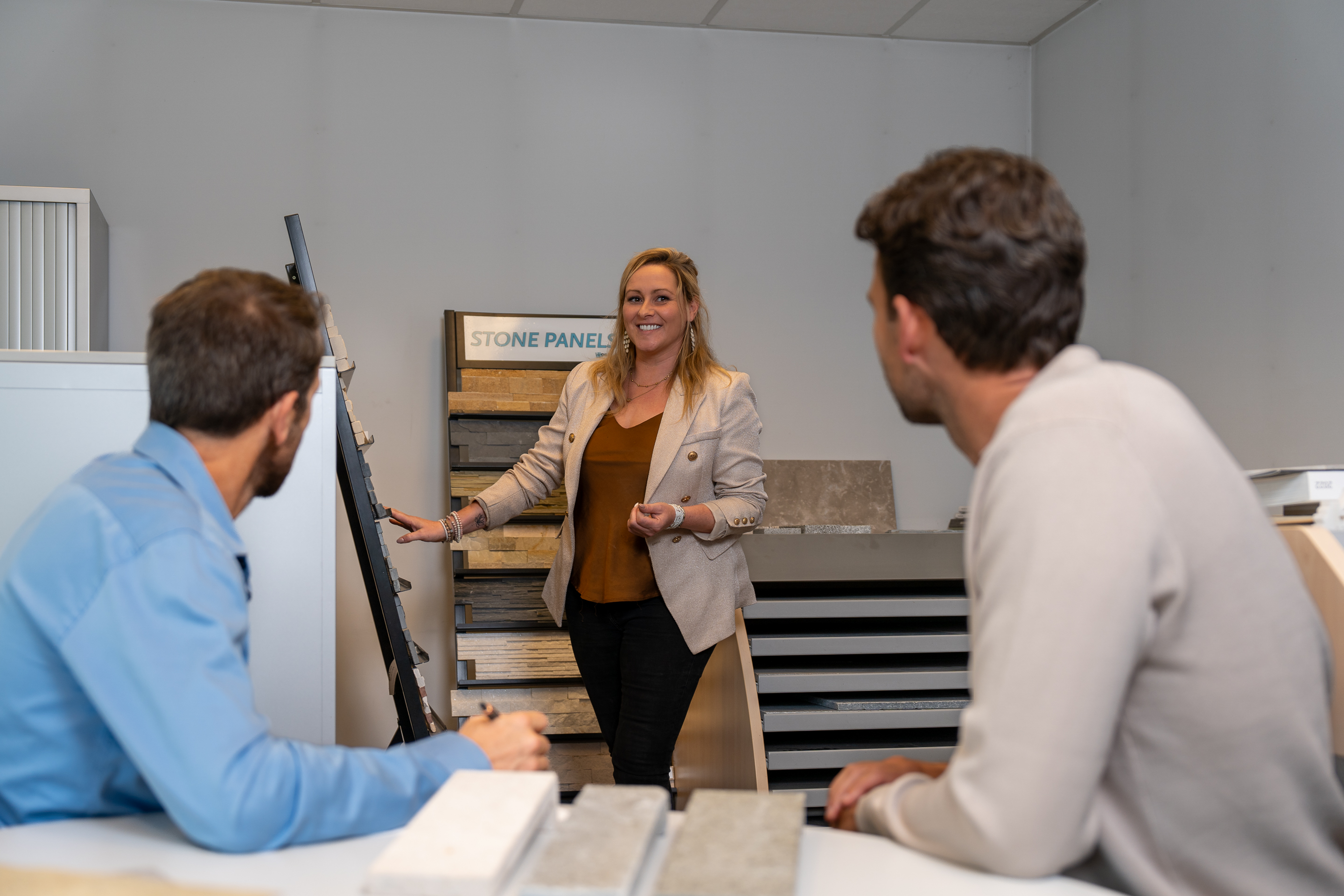 Een ervaren medewerker geeft deskundig advies aan 2 mannen om de juiste steenstrips te kiezen voor hun project.