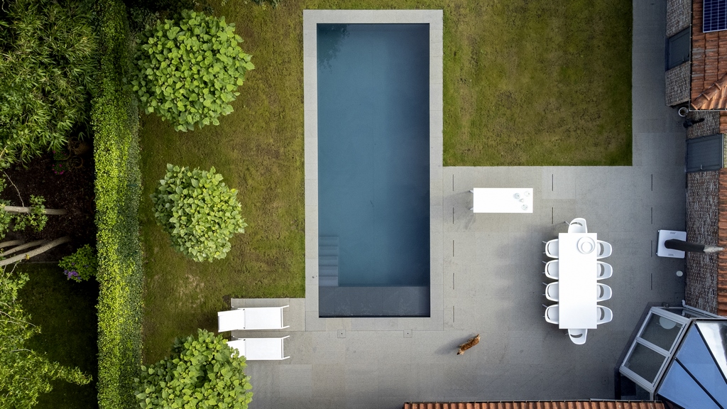 Bovenaanzicht van een tuin met rechthoekig zwembad en terras uit graniet.